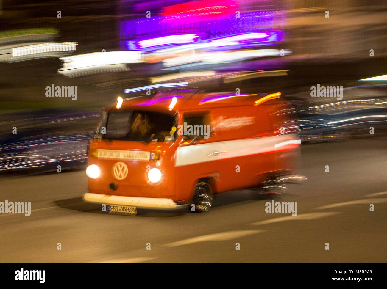 Ein rot-weißer historischer VW Bus T2 Bulli fährt nachts mit hoher Geschwindigkeit durch die belgische Stadt Spa. Ist der Anlaß nächtlichen Spritztour Banque D'Images