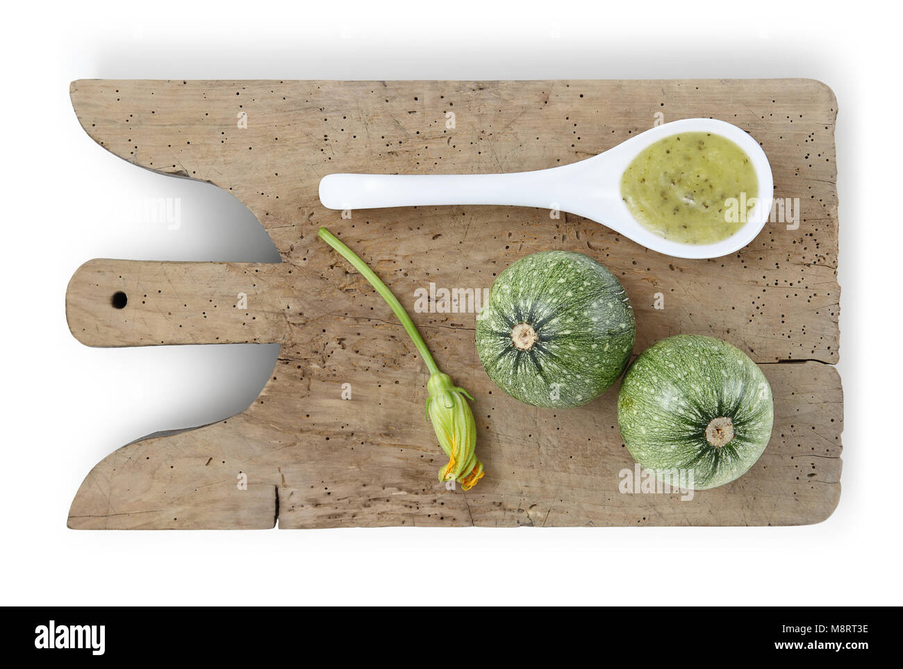 Les courgettes sur planche à découper en bois, fleur et la cuillère de sauce food top view isolé sur fond blanc Banque D'Images