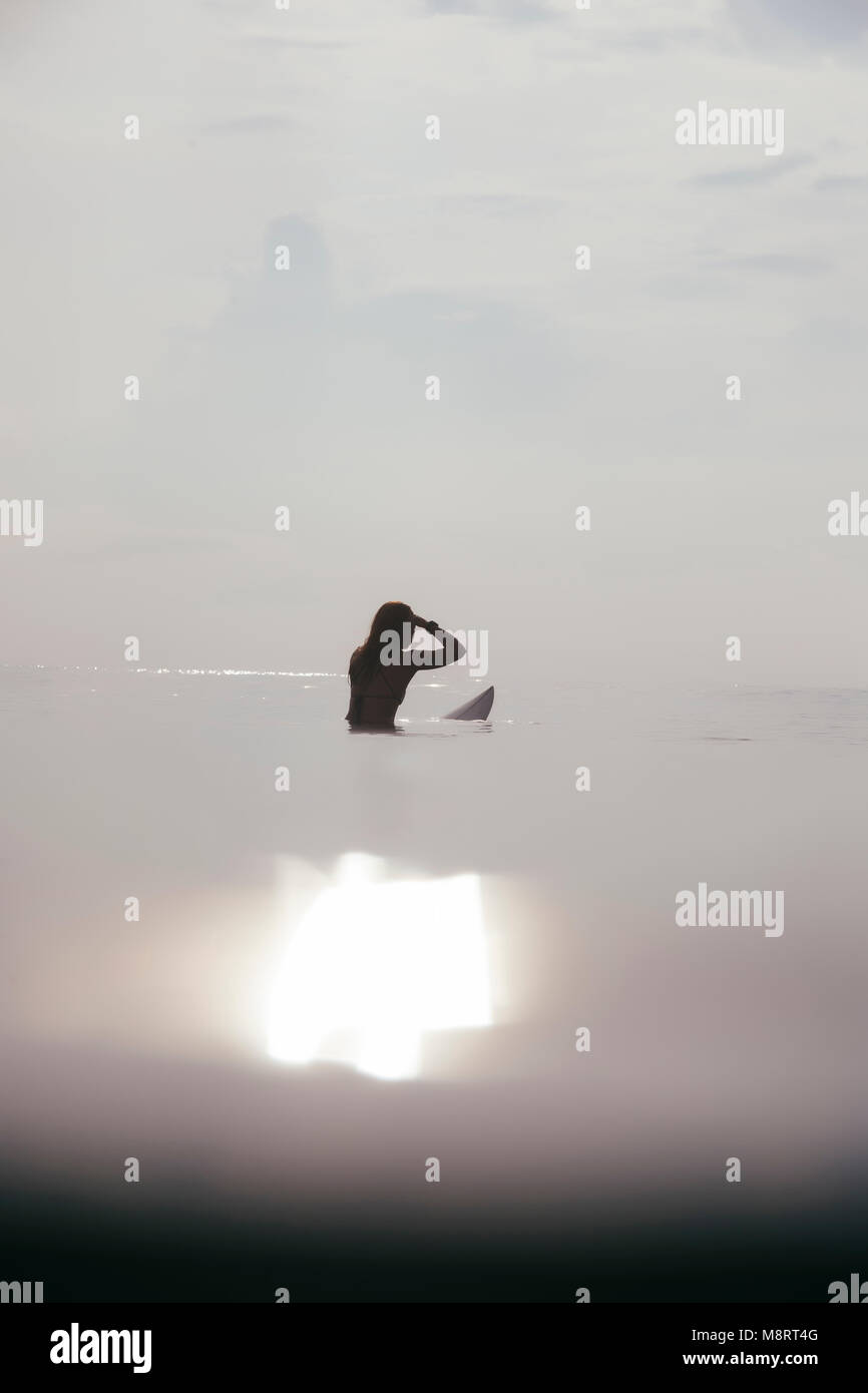 Femme surf en mer contre ciel lors de journée ensoleillée Banque D'Images