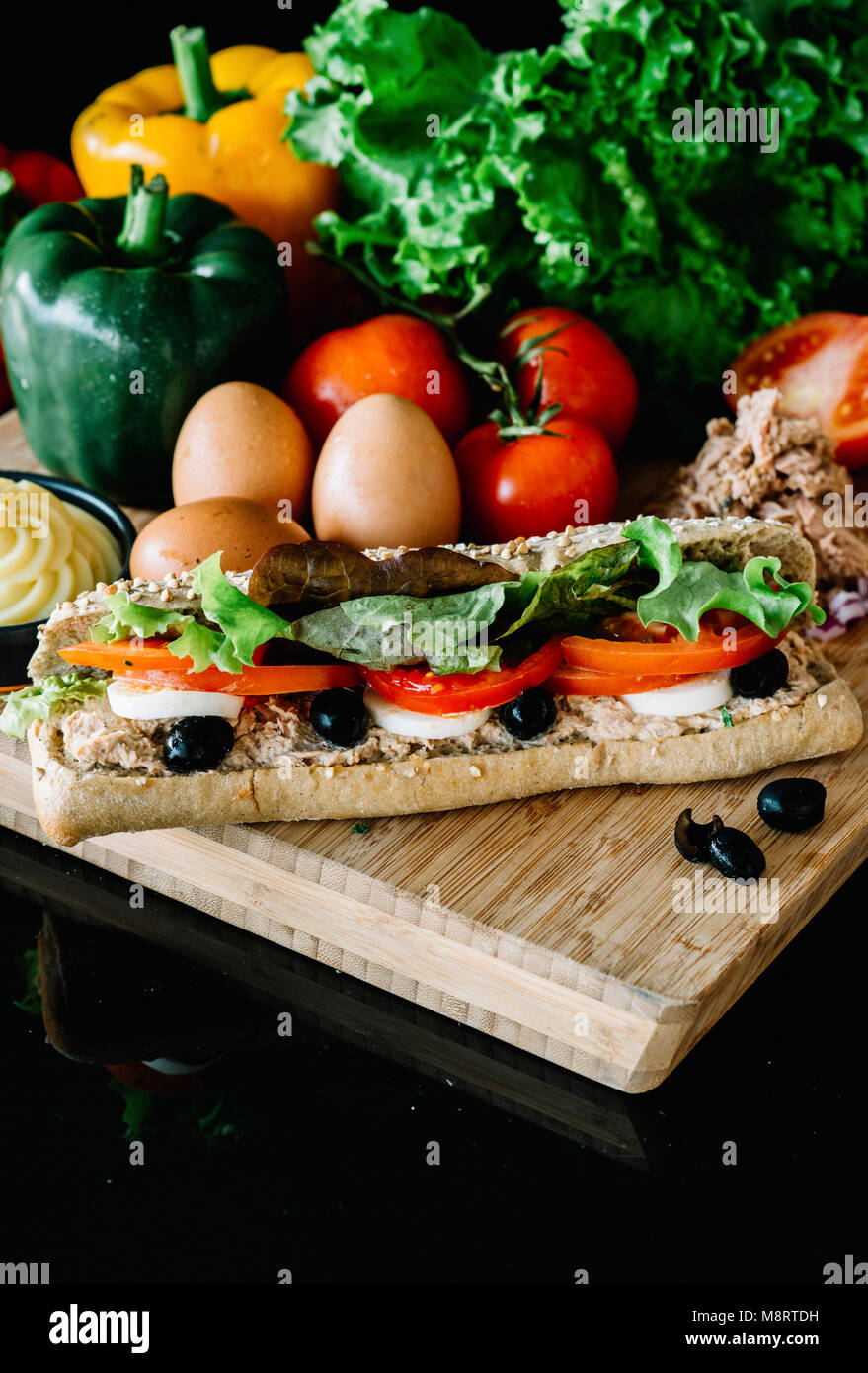 Close-up de sandwich avec des légumes sur une planche à découper sur fond noir Banque D'Images