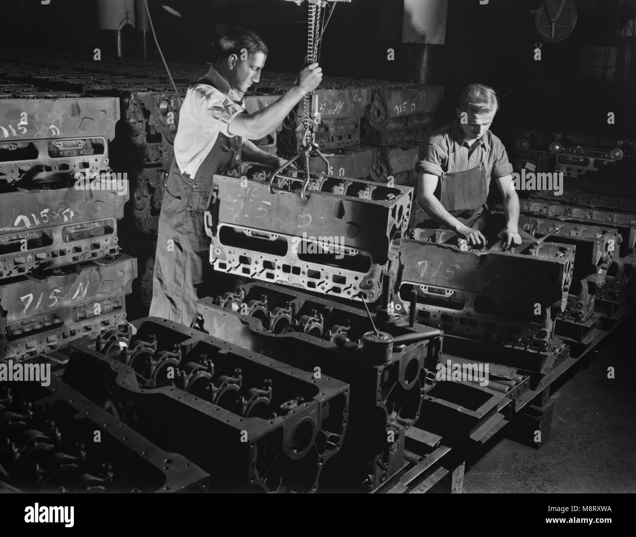 Deux travailleurs de mettre des blocs moteurs pour l'Armée de semi-chenillé sur ligne d'assemblage à l'usine convertie à la production de guerre, White Motor Company, Cleveland, Ohio, USA, Alfred T. Palmer pour l'Office of War Information, décembre 1941 Banque D'Images