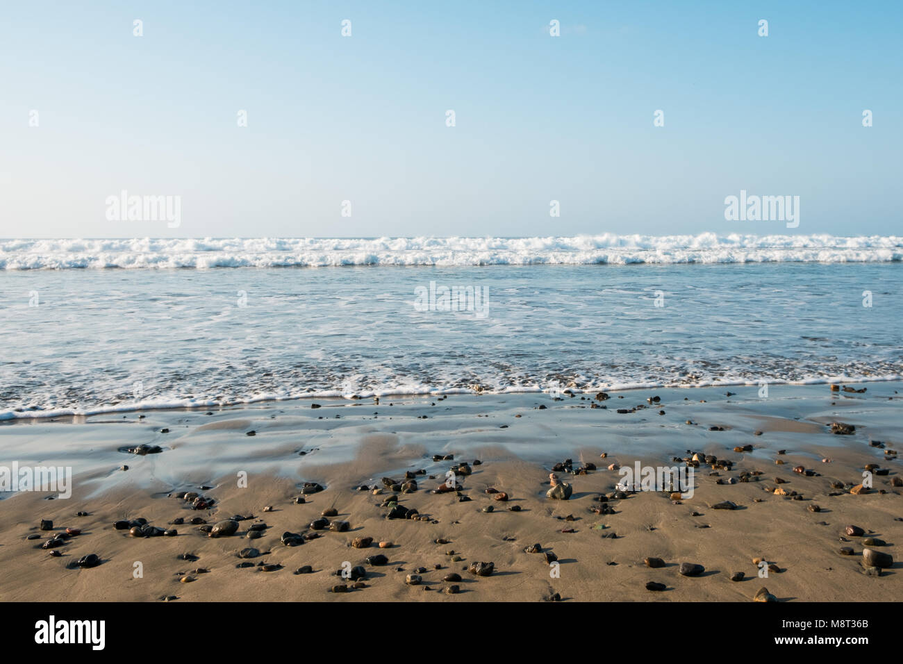 Paysage de plage - sable, pierres, eau et ciel bleu - Banque D'Images