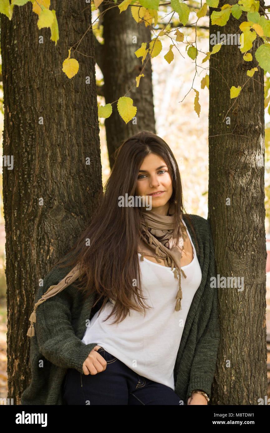 Jeune femme se reposant sur un tronc dans la forêt en automne. Banque D'Images