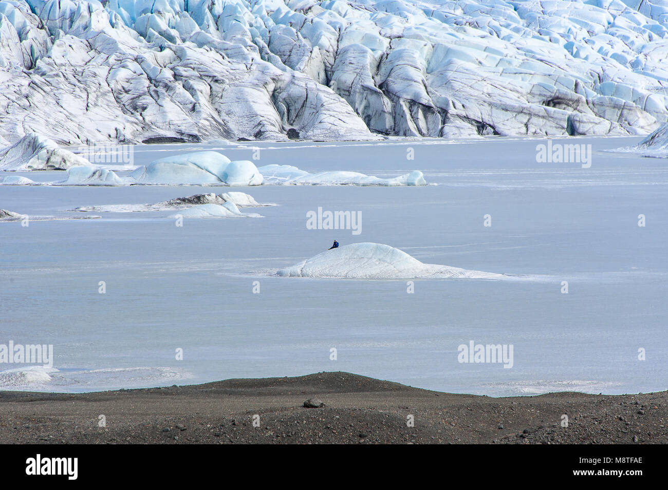 Un homme est assis sur un flux de glace entouré d'une mer de glace. Paysages étonnant à l'Falljokull Skaftafell, langue du glacier. Banque D'Images