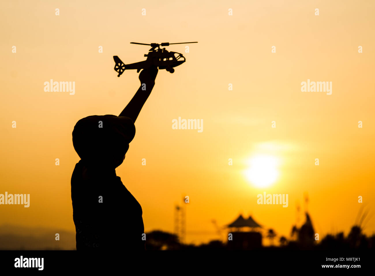 Silhouette Garçon jouant modèle d'hélicoptère avec du soleil. Banque D'Images