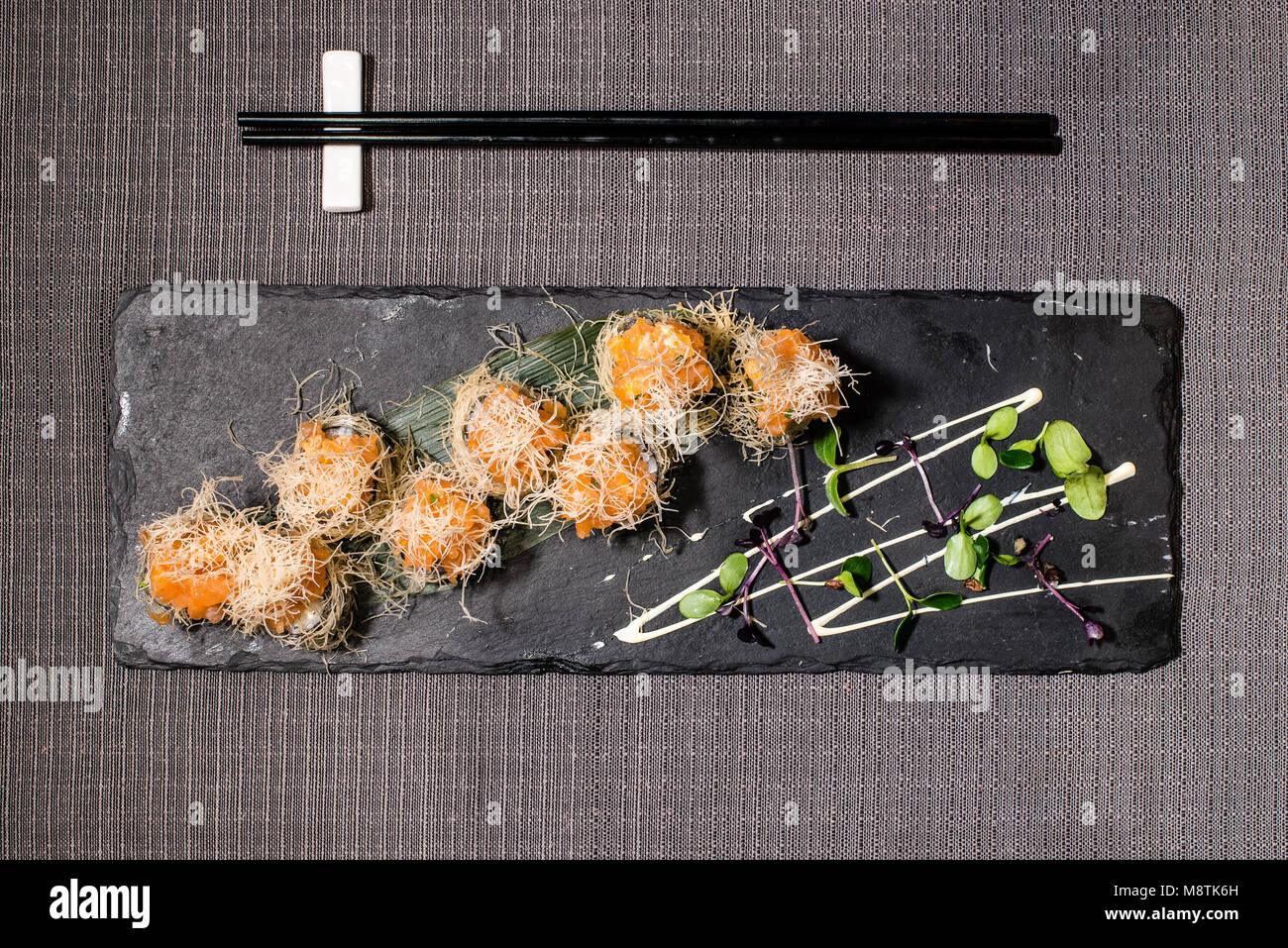 Uramaki avec riz et caviar servi avec roquette et crème aigre sur tableau noir Banque D'Images