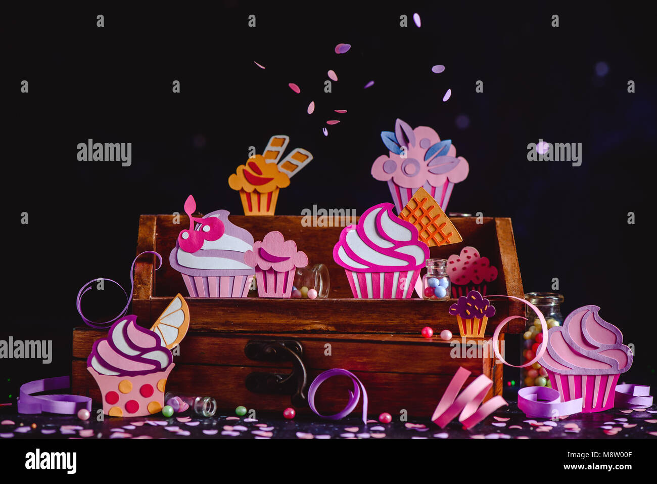 Cupcakes colorés collection sur une étagère en bois de confettis et paillettes. Assortiment de desserts Papercraft un fond sombre avec copie espace. Banque D'Images