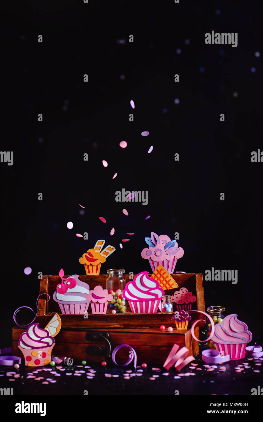 Concept de célébration. Cupcakes collection sur une étagère en bois avec des confettis et paillettes. Un assortiment coloré dessert papercraft dark backgroun Banque D'Images