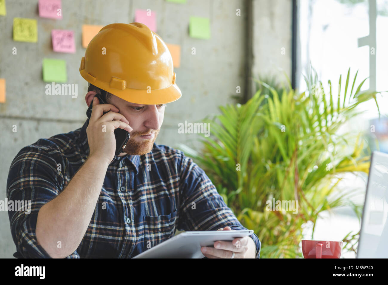 Parler avec l'ingénieur et de téléphone à la tablette à dans le bureau. Banque D'Images