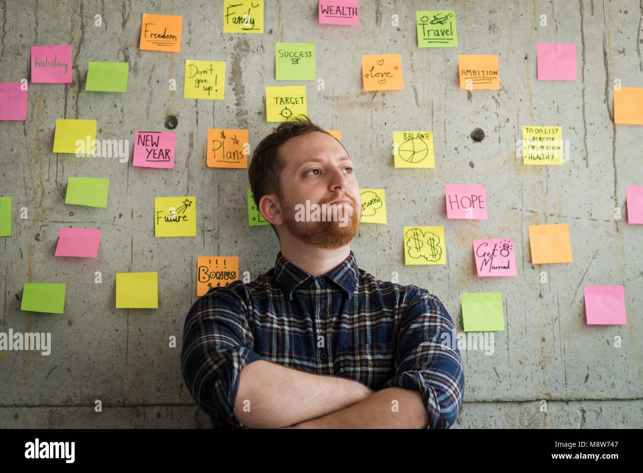 Homme heureux avec bras croisés sticky notes graphique sur mur de ciment. Concept de l'entrepreneur. Banque D'Images