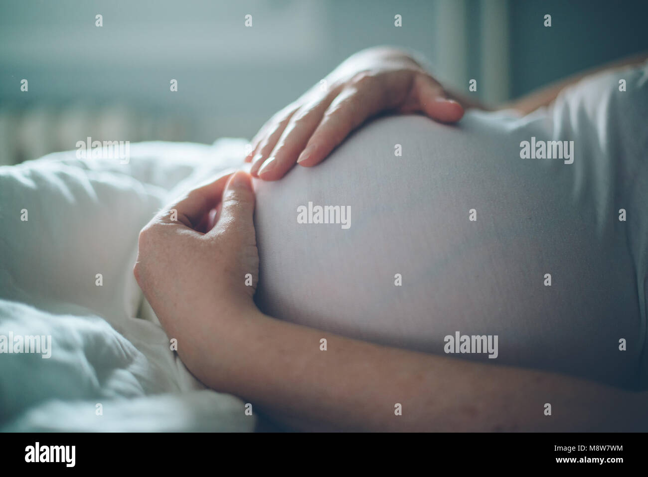 Femme enceinte ventre câlins dans la chambre à la maison juste avant le travail et l'accouchement, selective focus Banque D'Images