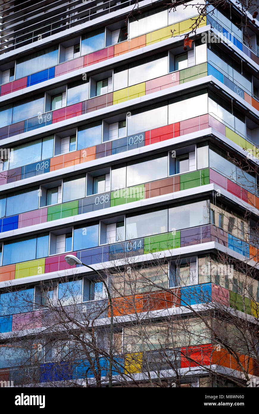 Vue de dessous d'un bâtiment moderne avec des balcons en verre de couleur et numérotées. Banque D'Images