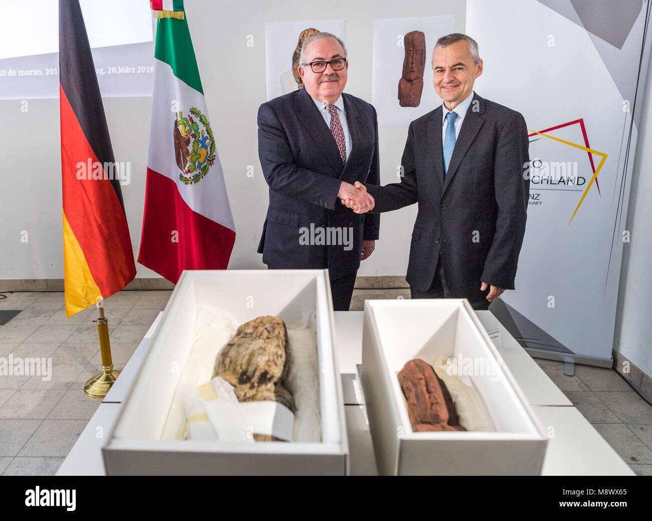 20 mars 2018, l'Allemagne, Munich : Rogelio Granguillhome (l-r), l'ambassadeur de l'governemt mexicain, et Rupert Gebhard, directeur de la collection archéologique de l'État de Bavière, serrer la main derrière deux artefacts Olmèque lors d'une conférence de presse par l'État bavarois Collection archéologique. Deux objets Olmèques autour de 3 000 ans ont été remis au gouvernement mexicain. Les objets avaient été pris hors du Mexique illégalement. Photo : Lino Mirgeler/dpa Banque D'Images