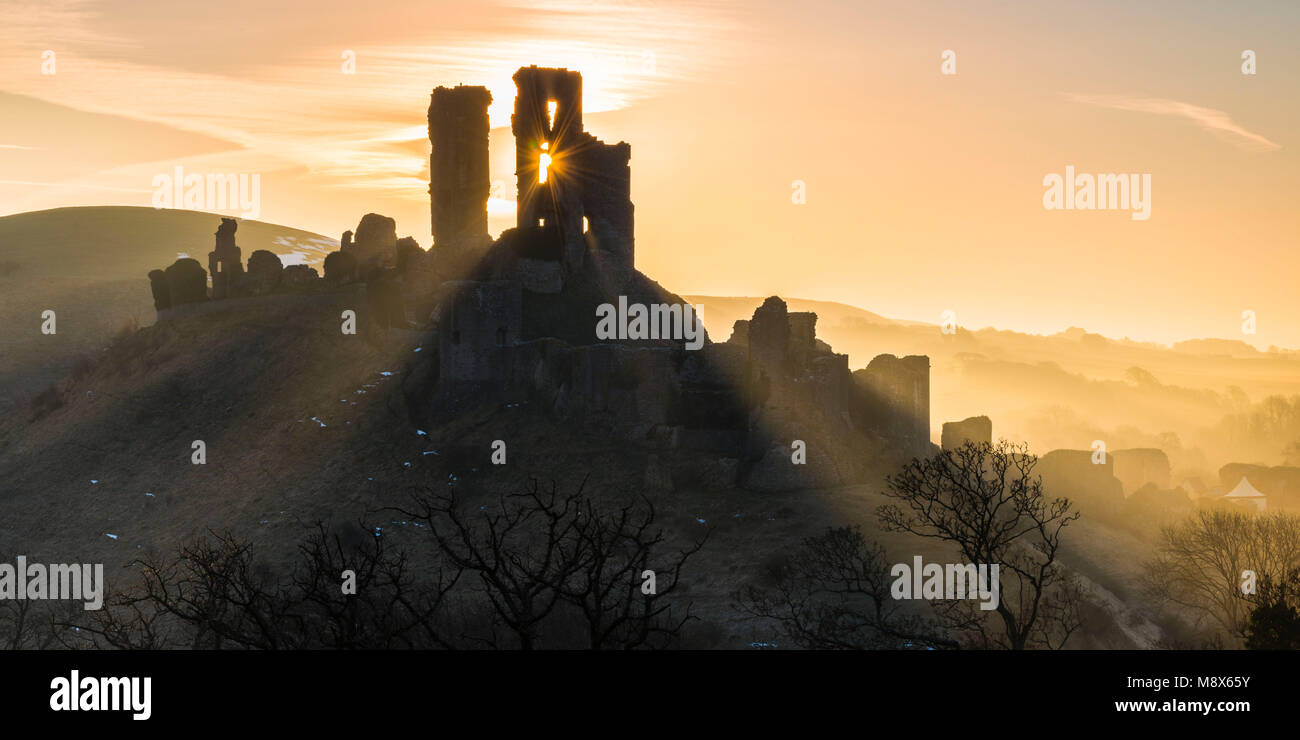 Château de Corfe, Dorset, UK. 21 mars 2018. Météo britannique. Poutres apparentes du soleil et autour de la silhouette des ruines du château de Corfe dans Dorset sur un matin lumineux peu après le lever du soleil. Crédit photo : Graham Hunt/Alamy Live News. Banque D'Images