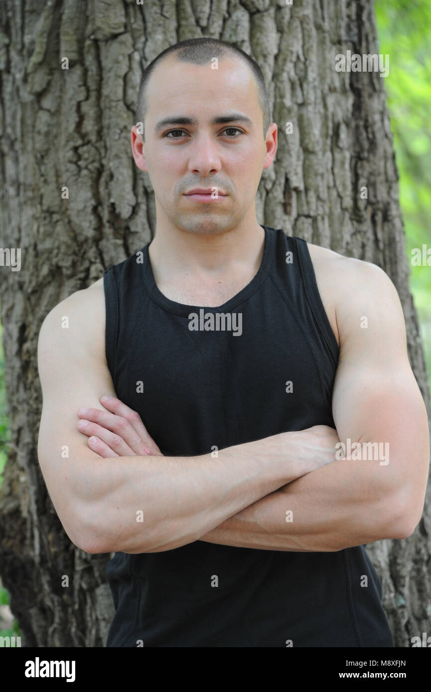 Jeune homme musclé crossing arms in forest Banque D'Images