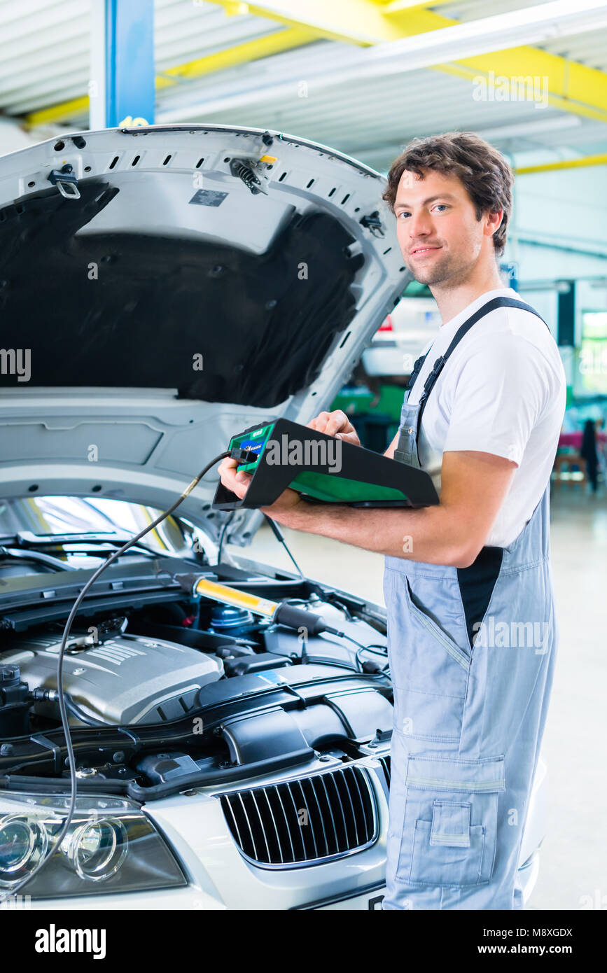 Mécanicien avec outil de diagnostic en atelier voiture Banque D'Images Mécanicien avec outil de diagnostic en atelier voiture Banque D'Images
