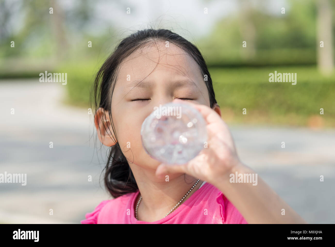 Happy Asian girl de boire une bouteille d'eau à l'extérieur. Banque D'Images