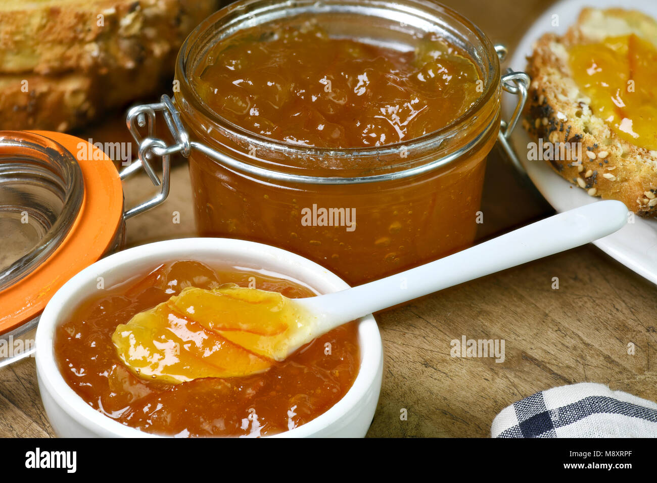 Confiture bio faits maison dans un petit plat blanc avec plus grande quantité dans un bocal posé sur une vieille table de cuisine en bois copy space Banque D'Images