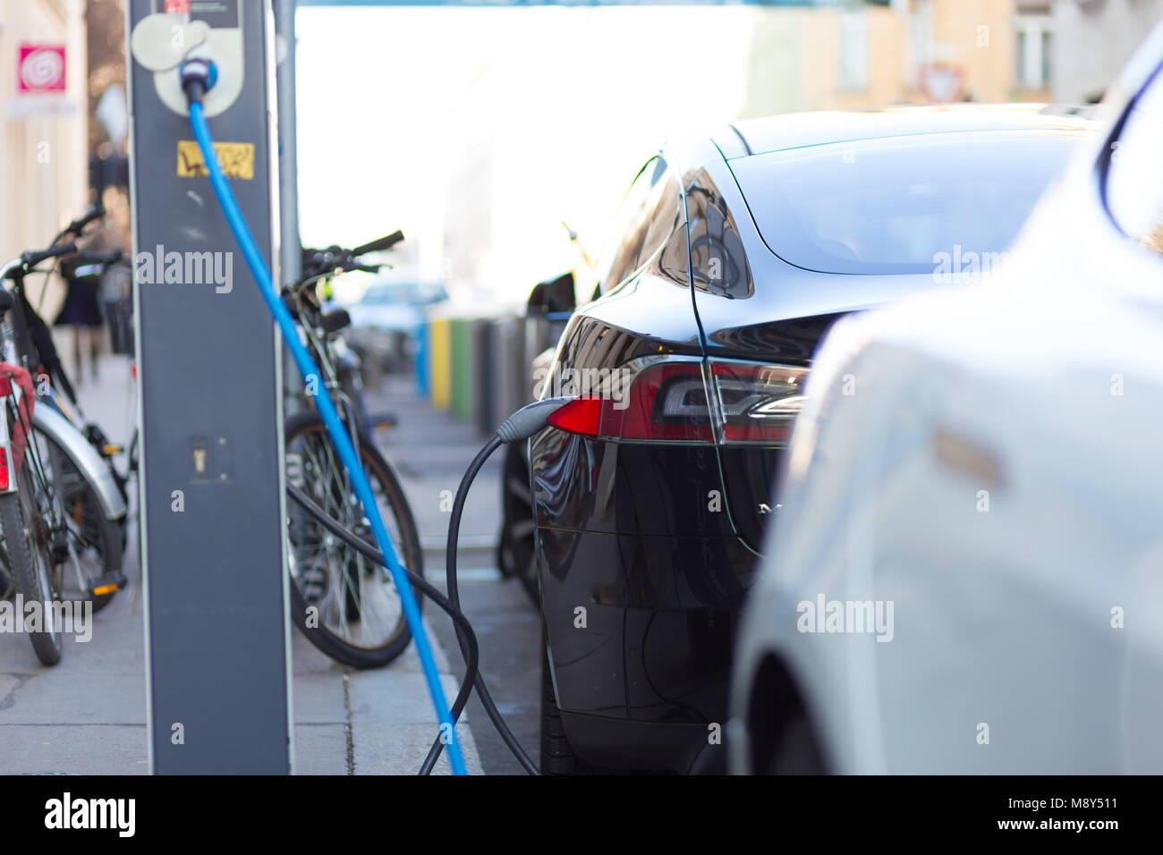 Voiture électrique moderne de charge sur la rue comme avenir de l'industrie automobile. Banque D'Images