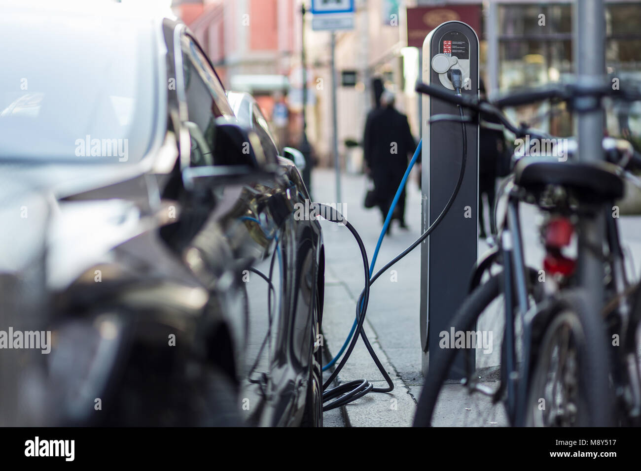 Voiture électrique moderne de charge sur la rue comme avenir de l'industrie automobile. Banque D'Images