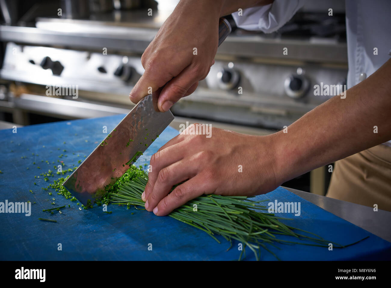Les mains du chef de cuisine restaurant la ciboulette coupe sur tableau bleu Banque D'Images