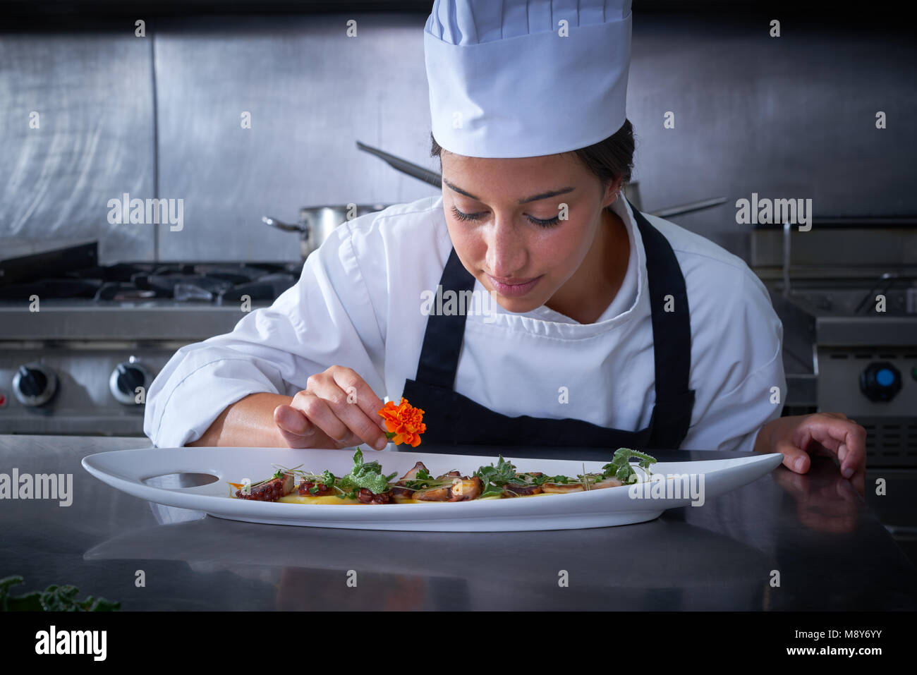Femme Chef de garnir en fleur plat à la cuisine en acier inoxydable Banque D'Images