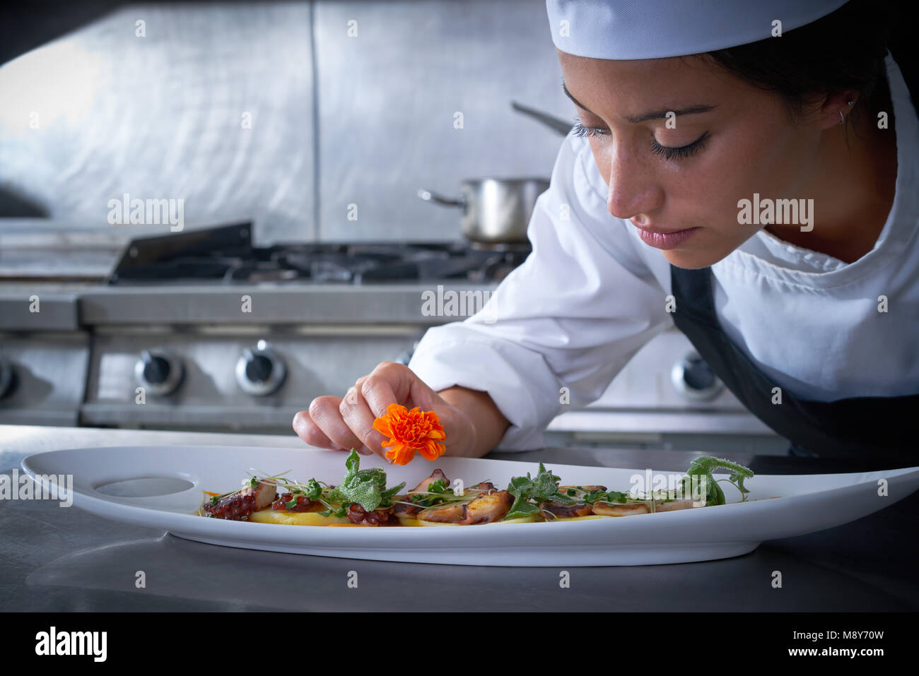 Femme Chef de garnir en fleur plat à la cuisine en acier inoxydable Banque D'Images