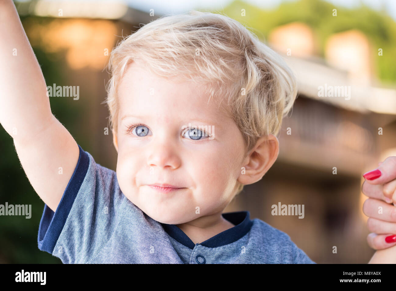 Magnifique petit garçon aux yeux bleus et aux cheveux blonds se tenir la main, lumière naturelle la photo en gros Banque D'Images