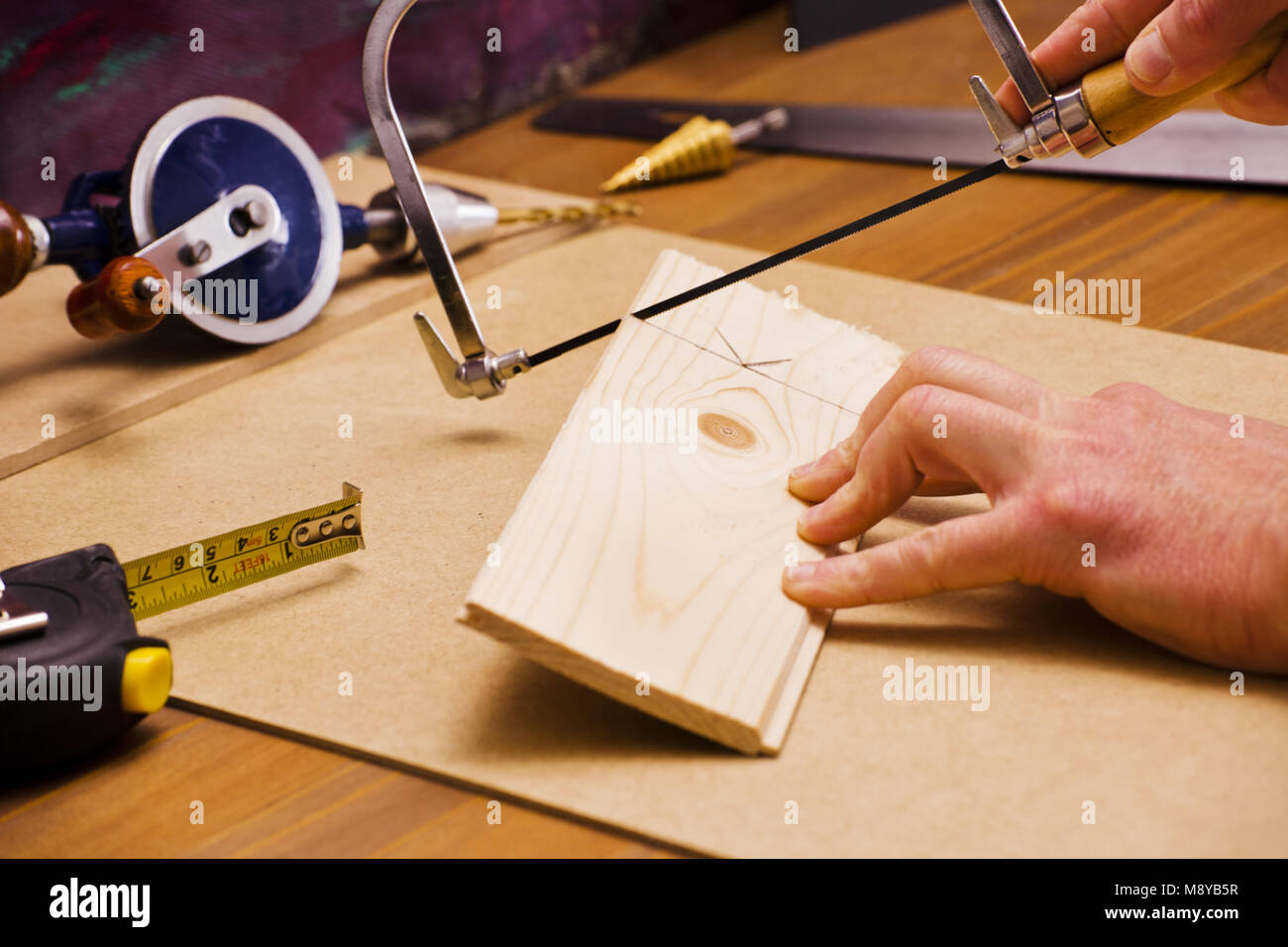 Carpenter a l'article de pine marqués d ligne et scier du bois de bord. Le Bureau a plusieurs outils de construction. Banque D'Images