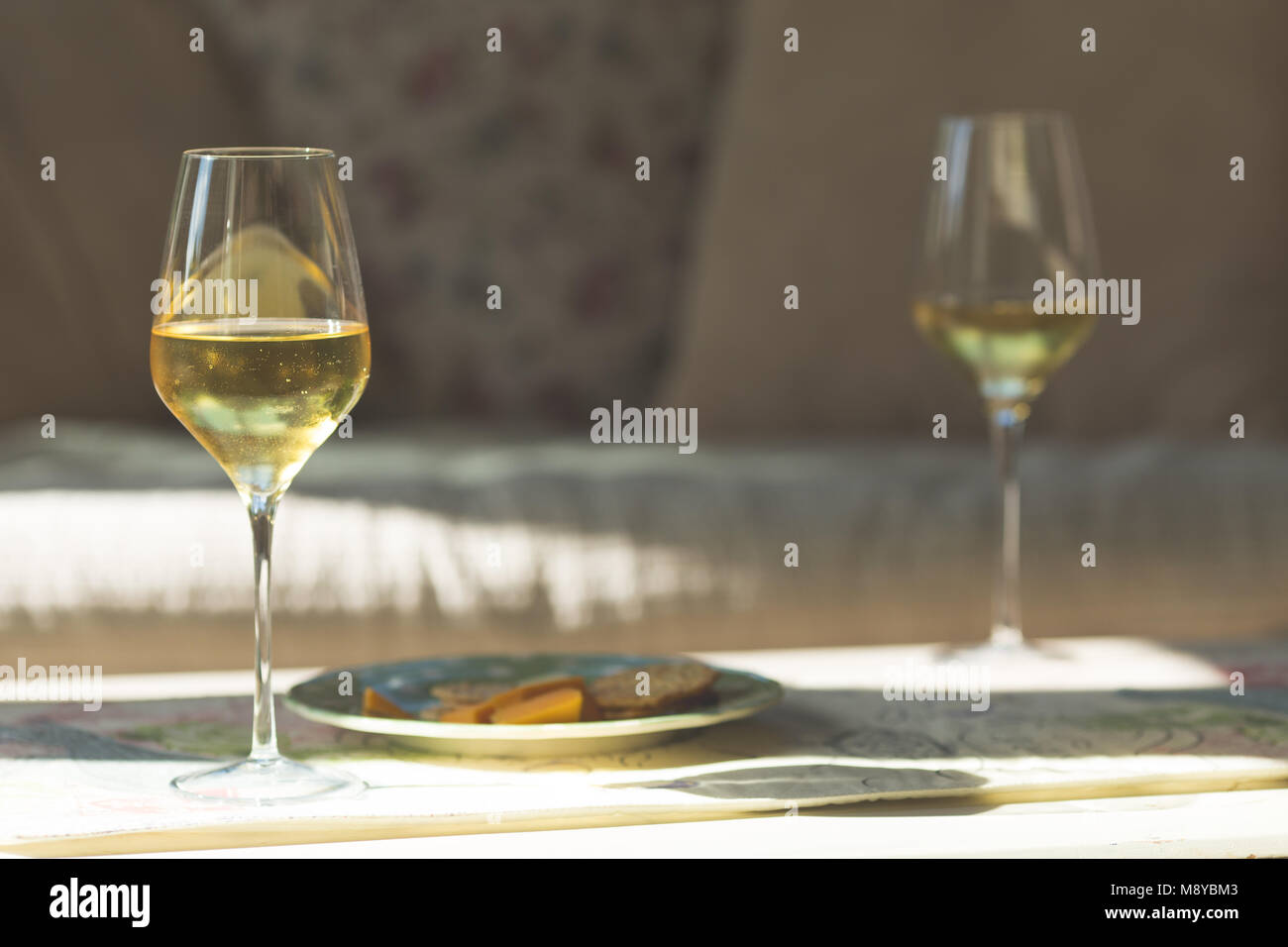 Deux verres de vin blanc sur une table avec un plateau de fromages Banque D'Images