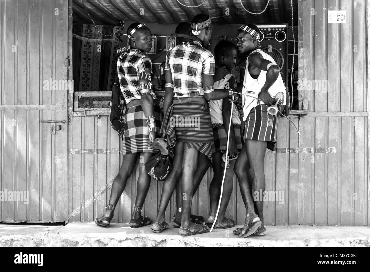 Les jeunes hommes à l'extérieur un Hamar téléphone mobile (téléphone cellulaire) Shop pendant leur visite hebdomadaire au marché de Dimeka Tribal, vallée de l'Omo, Ethiopie Banque D'Images