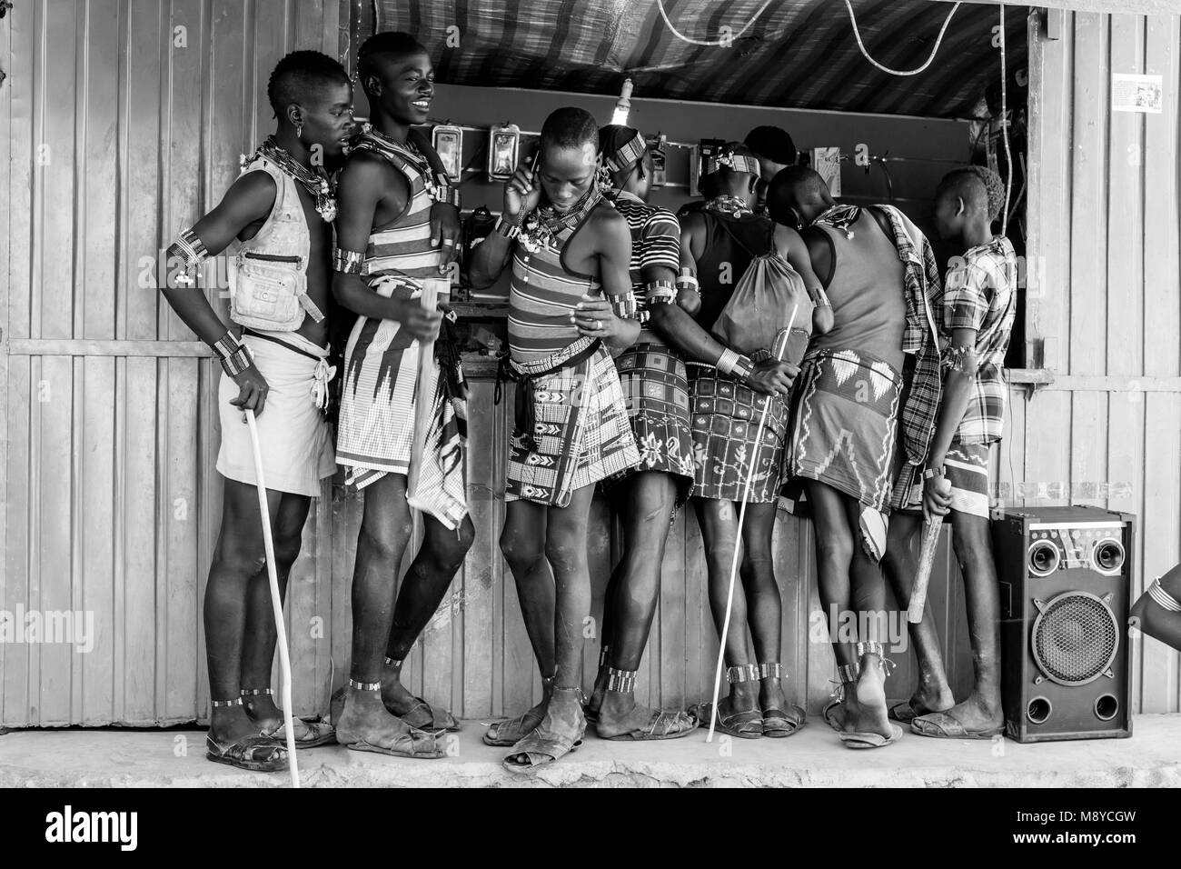 Les jeunes hommes à l'extérieur un Hamar téléphone mobile (téléphone cellulaire) Shop pendant leur visite hebdomadaire au marché de Dimeka Tribal, vallée de l'Omo, Ethiopie Banque D'Images