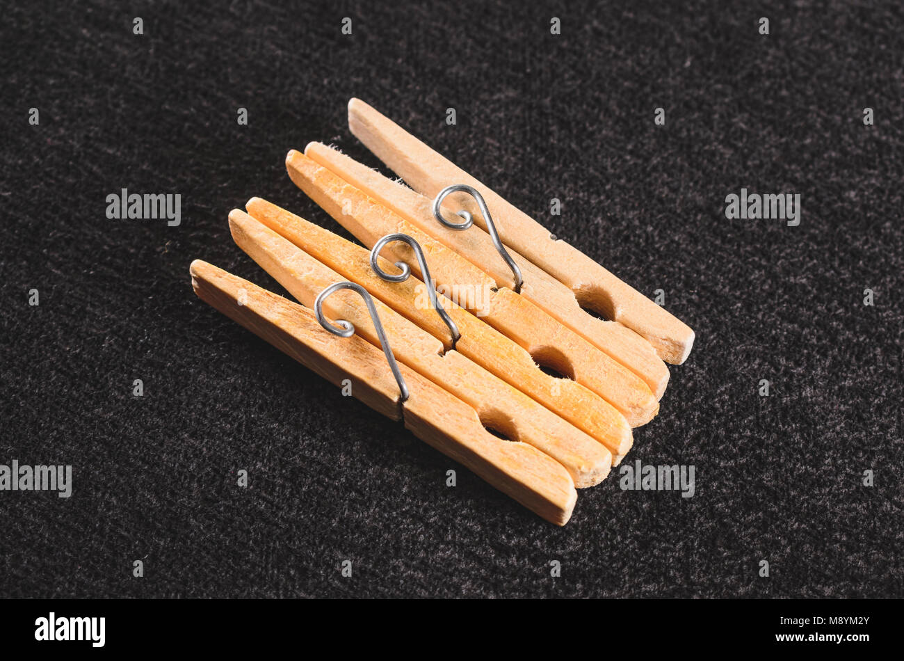 Trois colliers en bois clothespin isolé sur un fond texturé noir. Banque D'Images