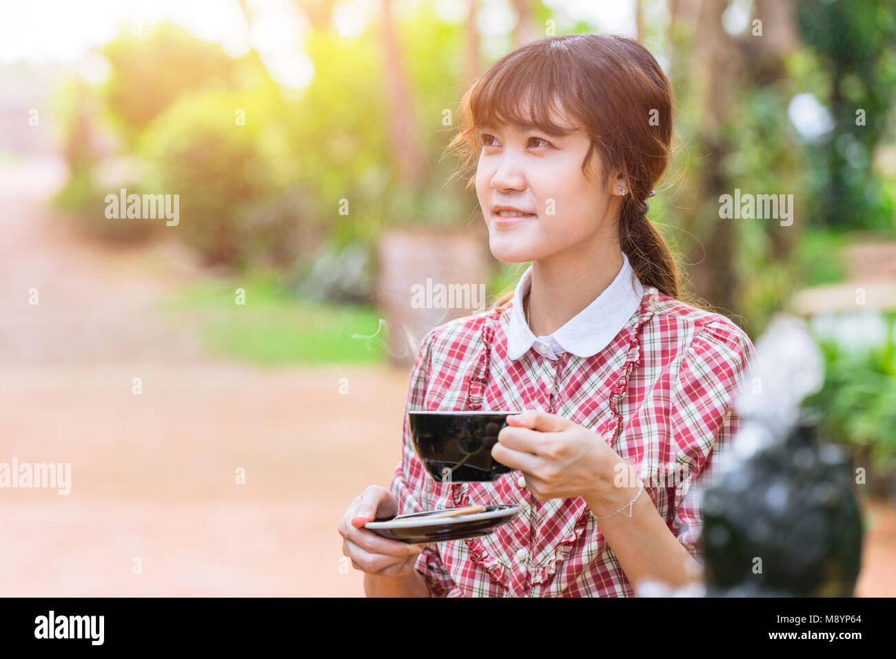 De belles femmes asiatiques avec boisson chaude le matin avec parc jardin contexte Banque D'Images