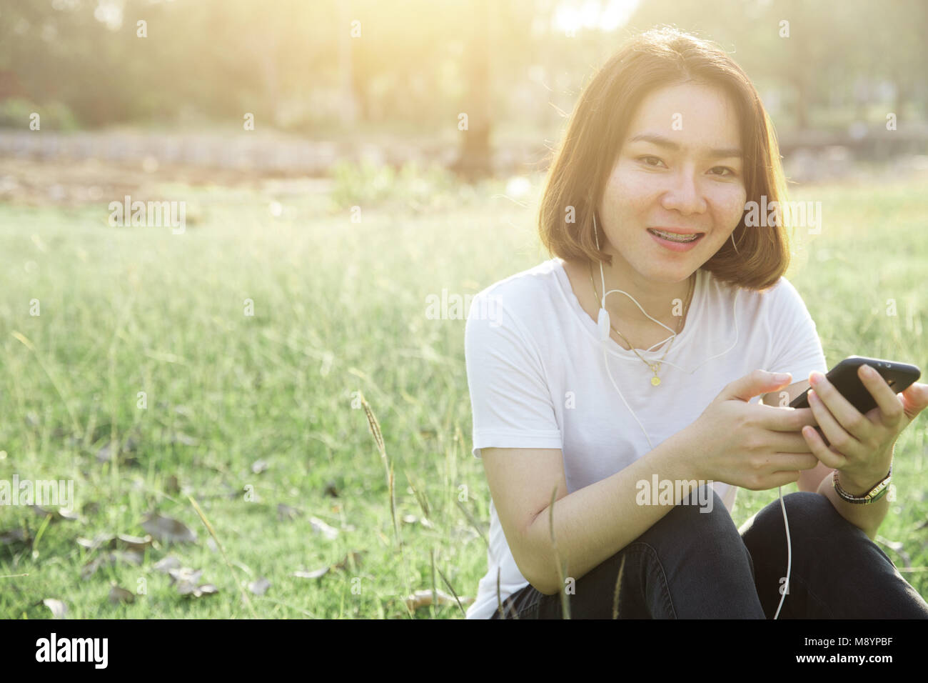 Cheveux courts Asian teen girl profiter avec la musique de téléphone mobile avec petits parler concept quotidien Banque D'Images