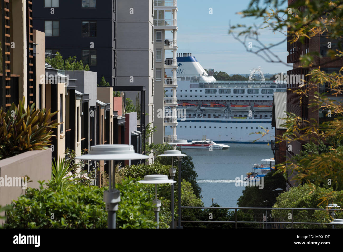 Une rue étroite à Pyrmont, Sydney avec appartements moderne de haute élévation de part et d'autre menant sur le port de Sydney et un bateau de croisière amarré, Australie Banque D'Images