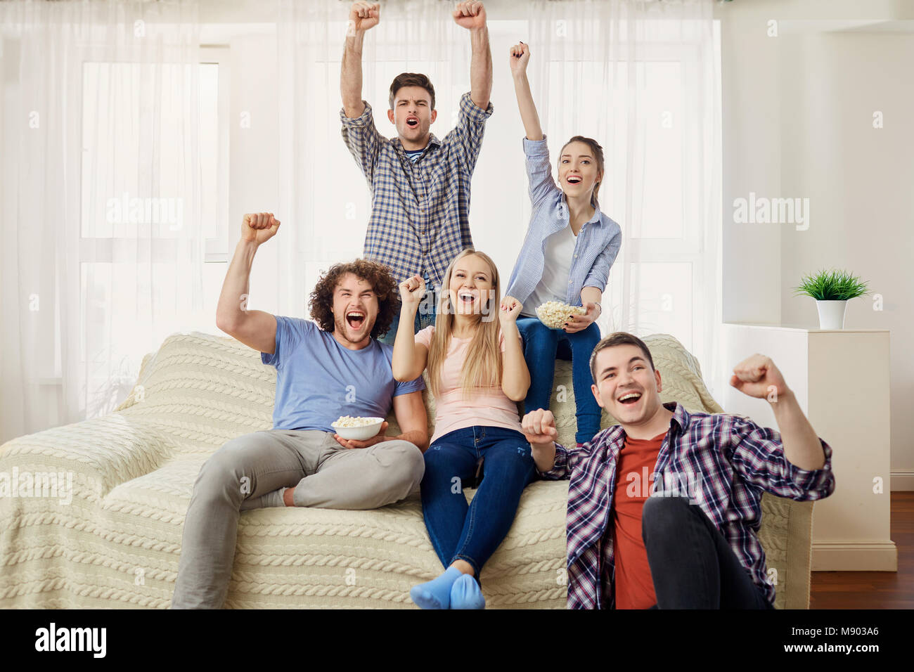 Un groupe d'amis des fans de regarder un sports TV assis sur un sof Banque D'Images