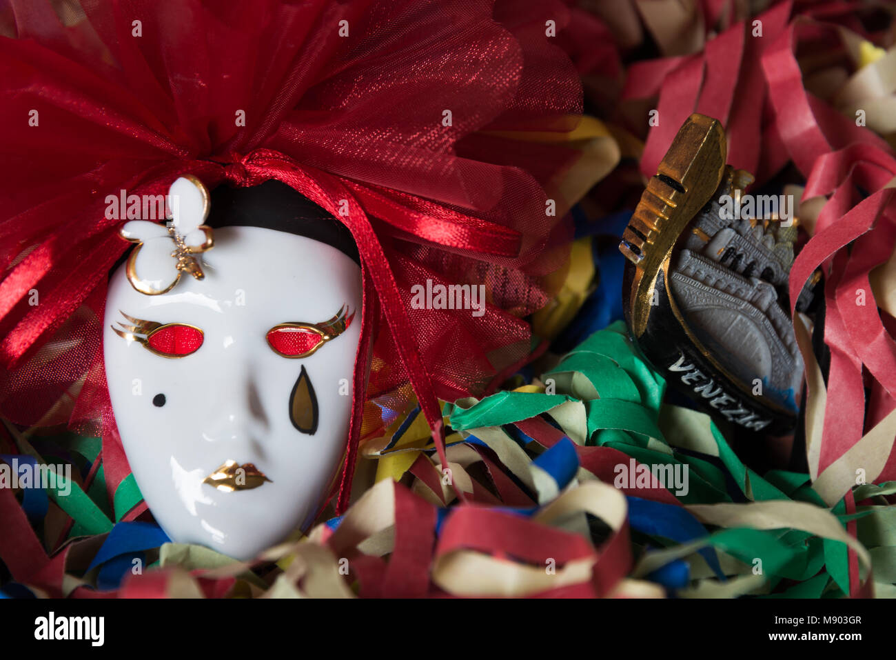 Close-up d'un masque de carnaval de Pierrot sur un arrière-plan avec une gondole vénitienne et de banderoles colorées Banque D'Images