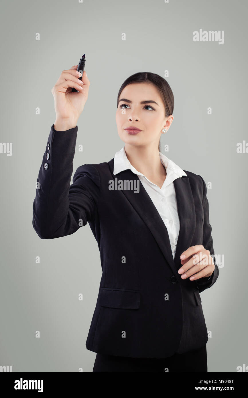 Jeune femme d'affaires en costume noir tenir Pen et l'écriture Banque D'Images