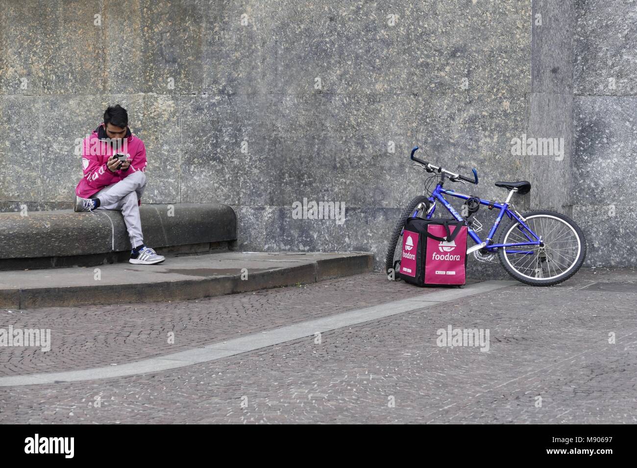 Livraison de nourriture Foodora carrybag travailleur assis près de vélo et consulting son smartphone à Turin Italie 12 mars 2018 Banque D'Images