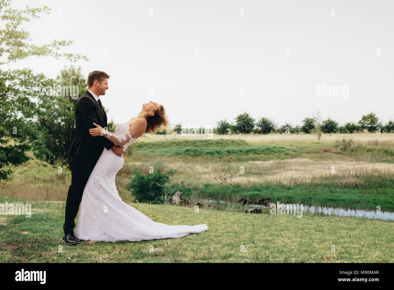 Toute la longueur du couple debout ensemble dans un parc. Mariée et le marié avant la cérémonie de mariage. Banque D'Images Toute la longueur du couple debout ensemble dans un parc. Mariée et le marié avant la cérémonie de mariage. Banque D'Images