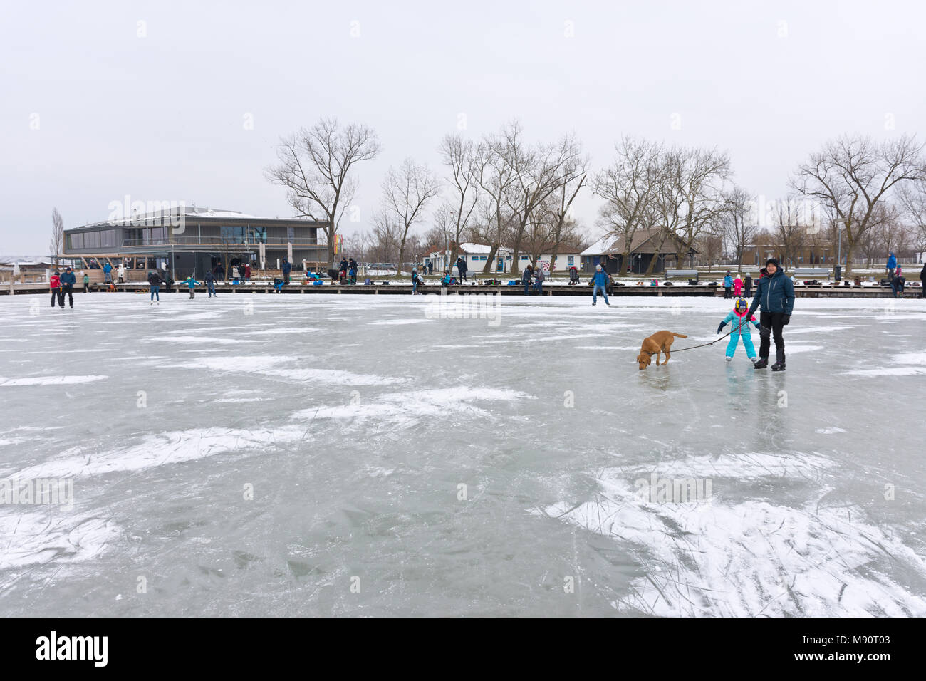 Les gens de patinage sur le lac gelé de Neusiedl dans nuageux terne et froid de l'hiver Banque D'Images