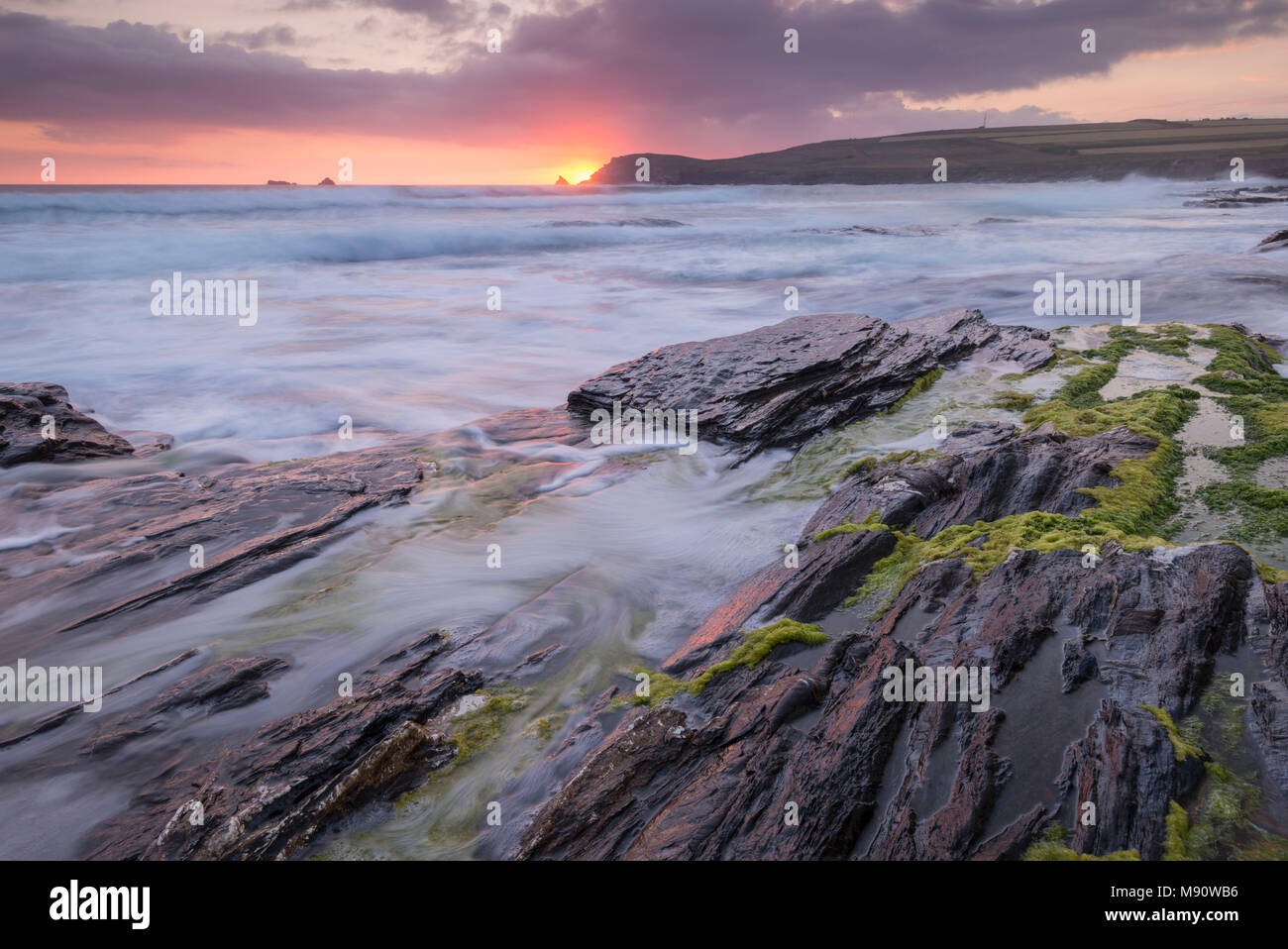 Les vagues déferlent sur les rives rocheuses de la Baie d'objets piégés au coucher du soleil, Cornwall, Angleterre. L'été (juillet) 2017. Banque D'Images