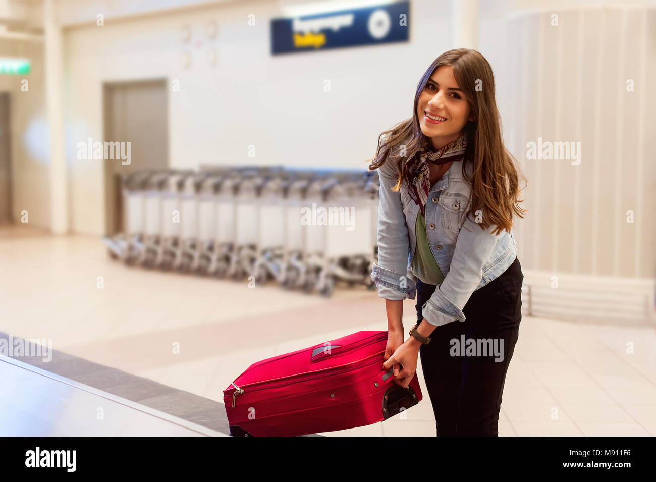 Jeune femme passager en 20s la collecte ses bagages à courroie du convoyeur dans salon arrivée d'aérogare Banque D'Images