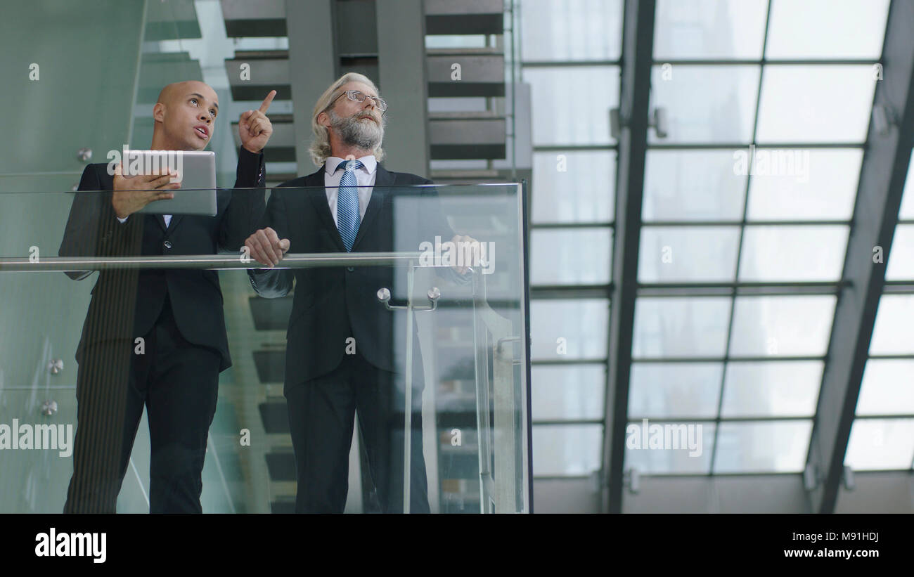 Deux professionnels du design moderne en verre et d'acier pour le bâtiment ayant une discussion à l'aide de tablette numérique. Banque D'Images