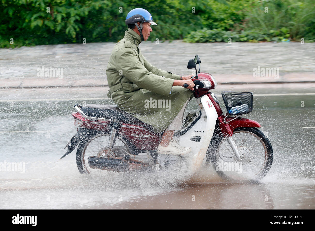 De fortes pluies de mousson. Homme conduisant une moto. Phu Quoc. Le Vietnam. Banque D'Images