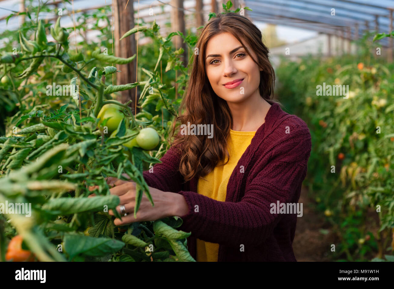 Belle jeune femme le jardinage et smiling at camera. Les émissions de produits. La production alimentaire. Banque D'Images