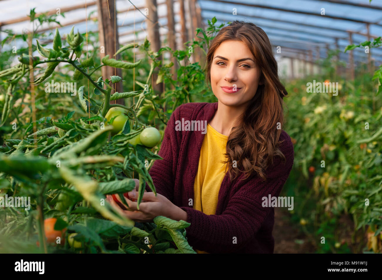 Belle jeune femme le jardinage et smiling at camera. Les émissions de produits. La production alimentaire. Banque D'Images