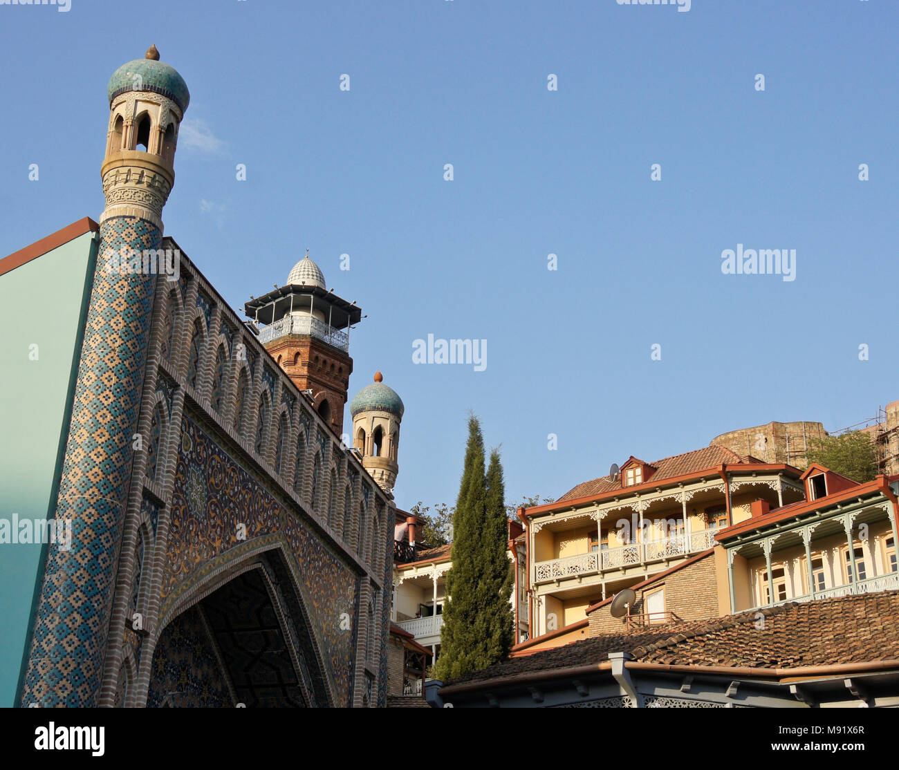 La façade carrelée de bleu de bains Orbeliani, rouge-brique minaret d'une mosquée, les maisons dans la vieille ville et la forteresse de Narikala sur hill, Tbilissi, Géorgie Banque D'Images