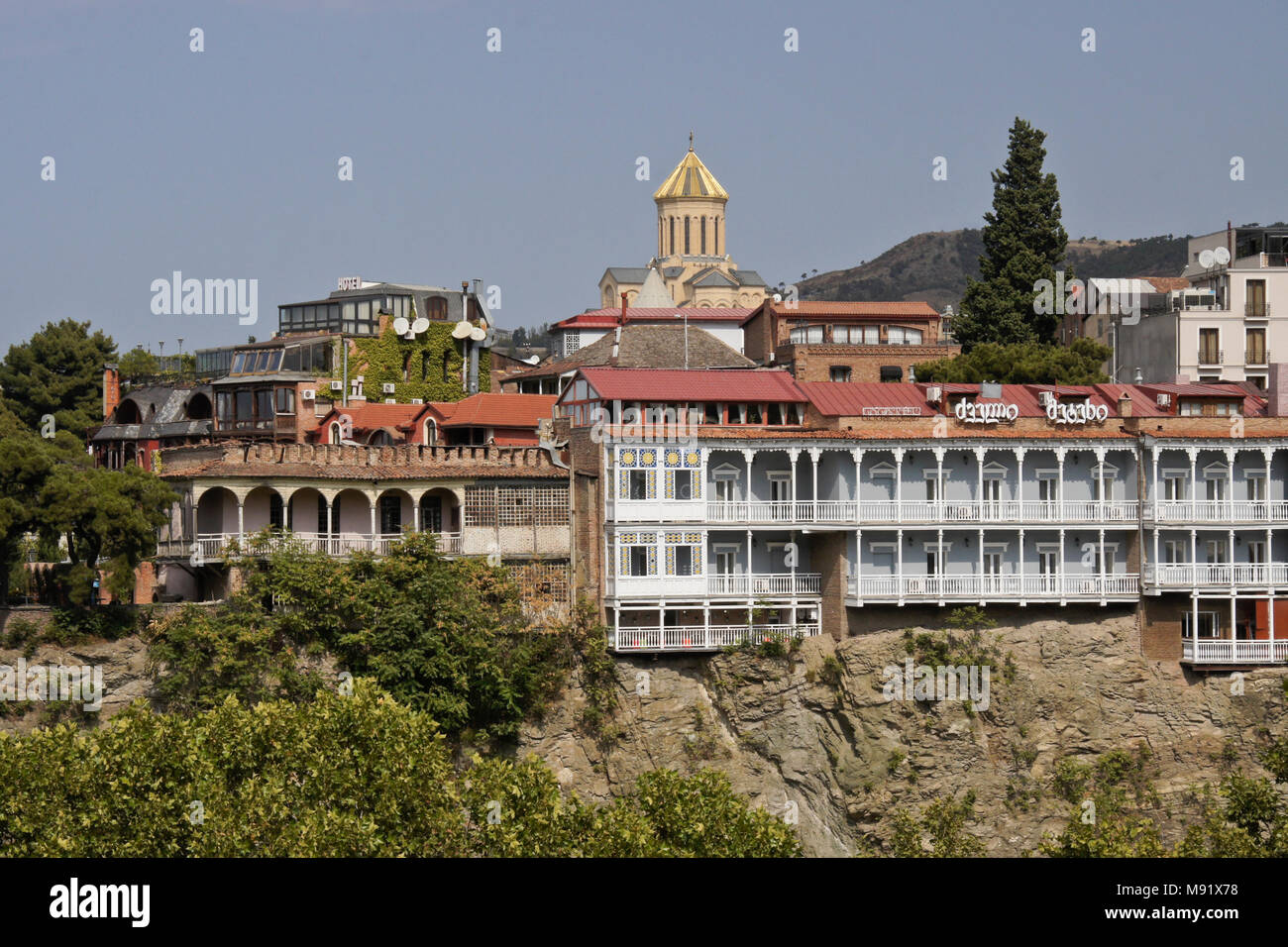L'hôtel Old Metekhi sur une falaise rocheuse au-dessus de la rivière Mtkvari avec Tsminda Sameba (sainte trinité) Cathédrale en arrière-plan, Tbilissi, Géorgie Banque D'Images